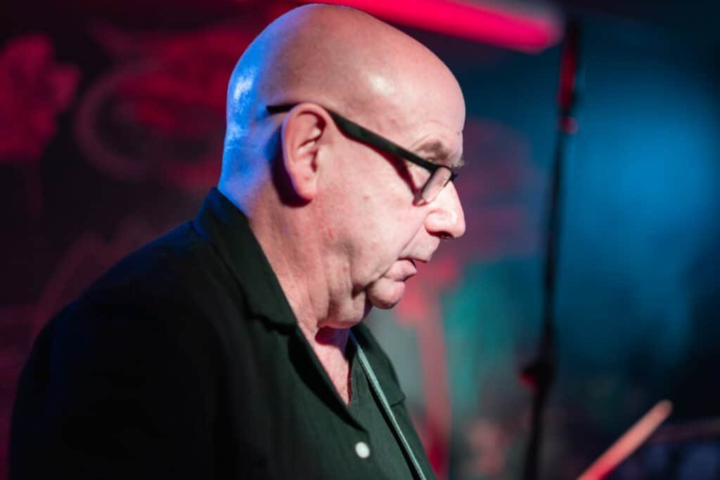 Bald musician performing on stage in dim lighting