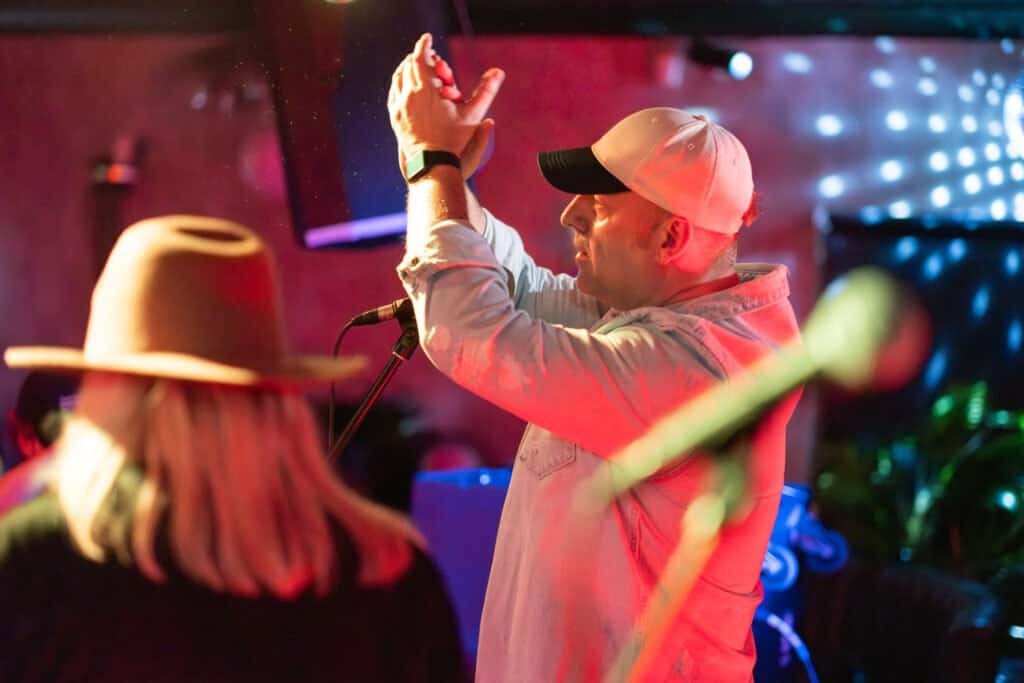 Musician performs energetically on stage with vibrant lighting