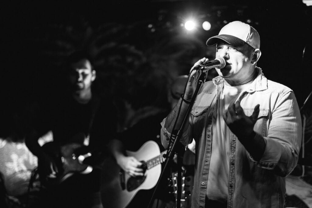 Singer performs live on stage with guitarist in background