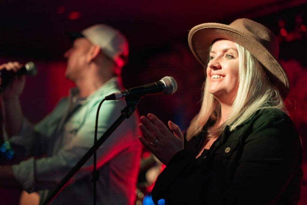 Smiling woman singing on stage with microphone in hand