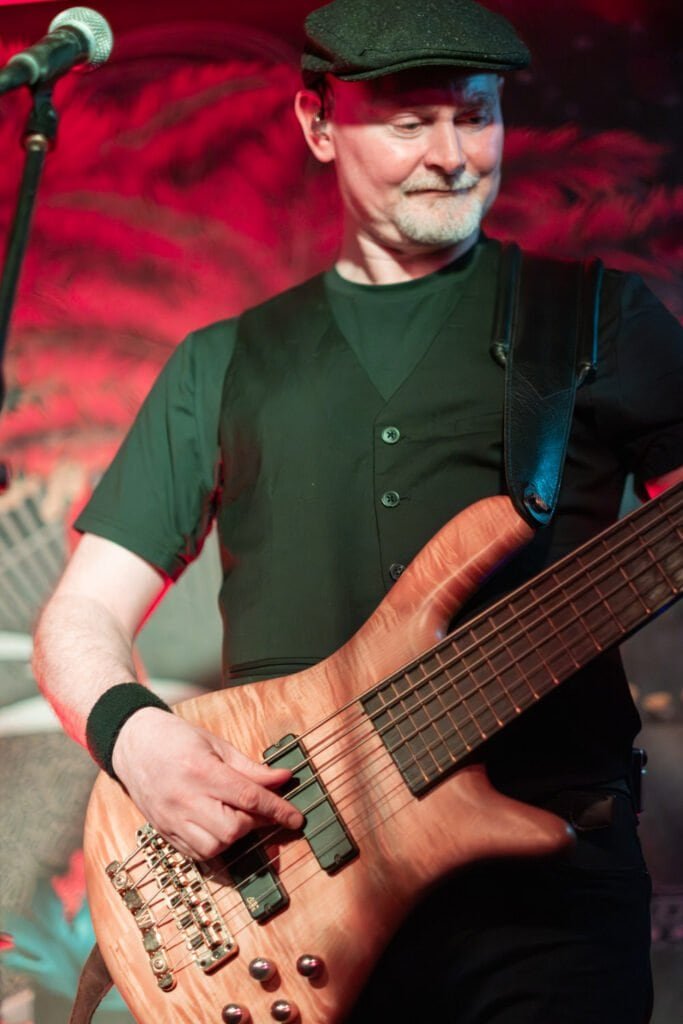 Man playing bass guitar on stage in vibrant lighting