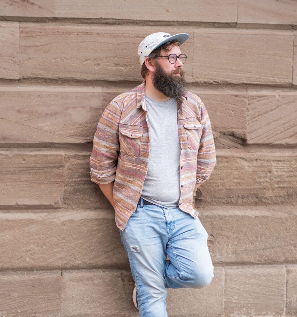 Steven Mitchell standing against a textured stone wall