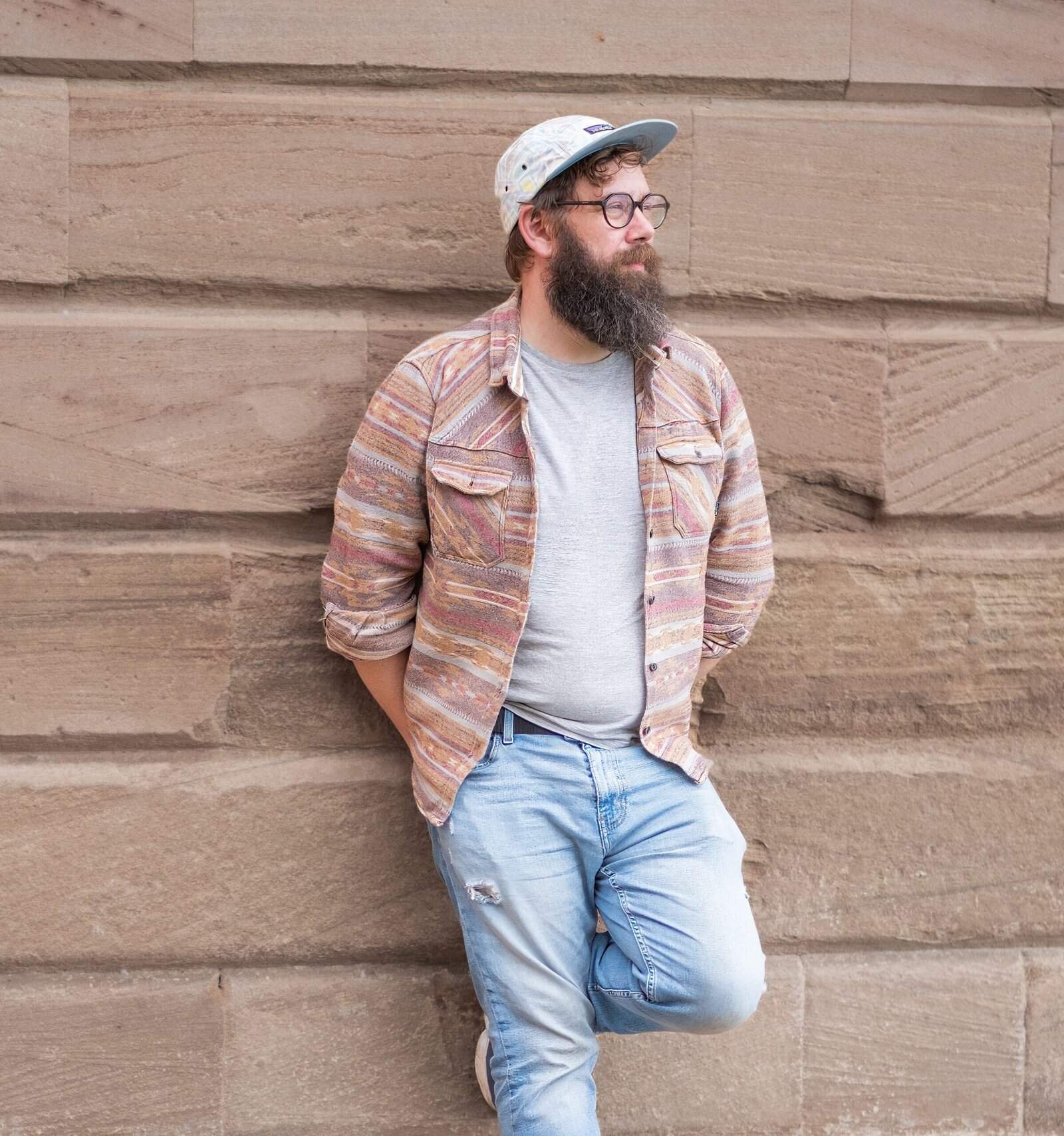 Steven Mitchell standing against a textured stone wall