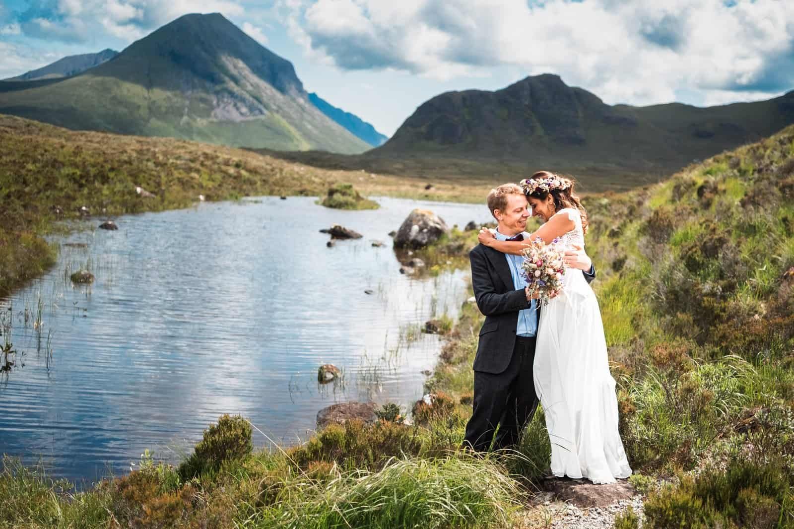 Bride and groom embrace on their elopement by scenic Isle of Skye landscape